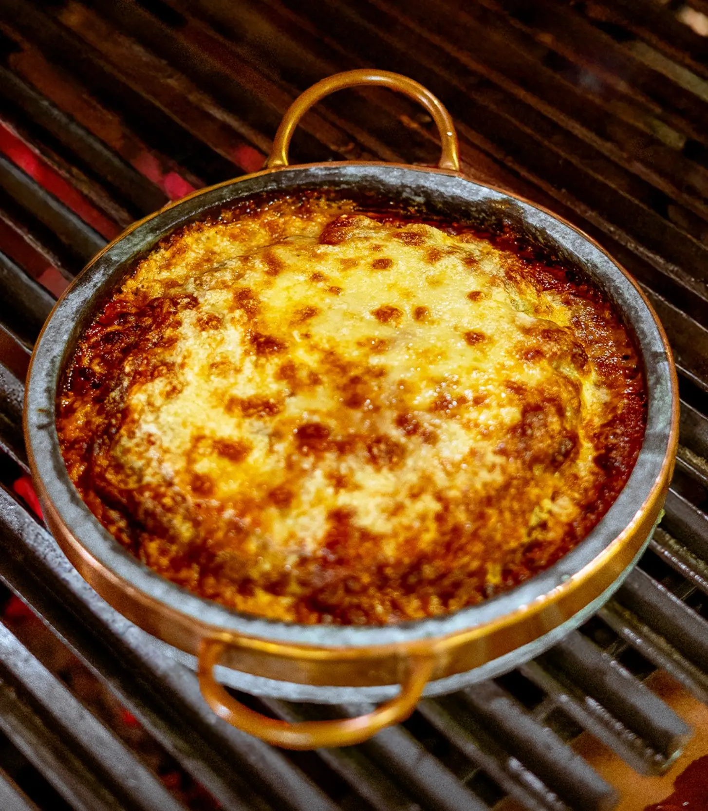 Parmegiana gratinada em panela de pedra sobre a brasa